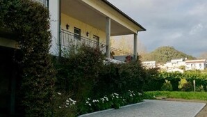 En bygning med en overdækket veranda, en stenhusgang og et bjergrigt landskab i baggrunden.