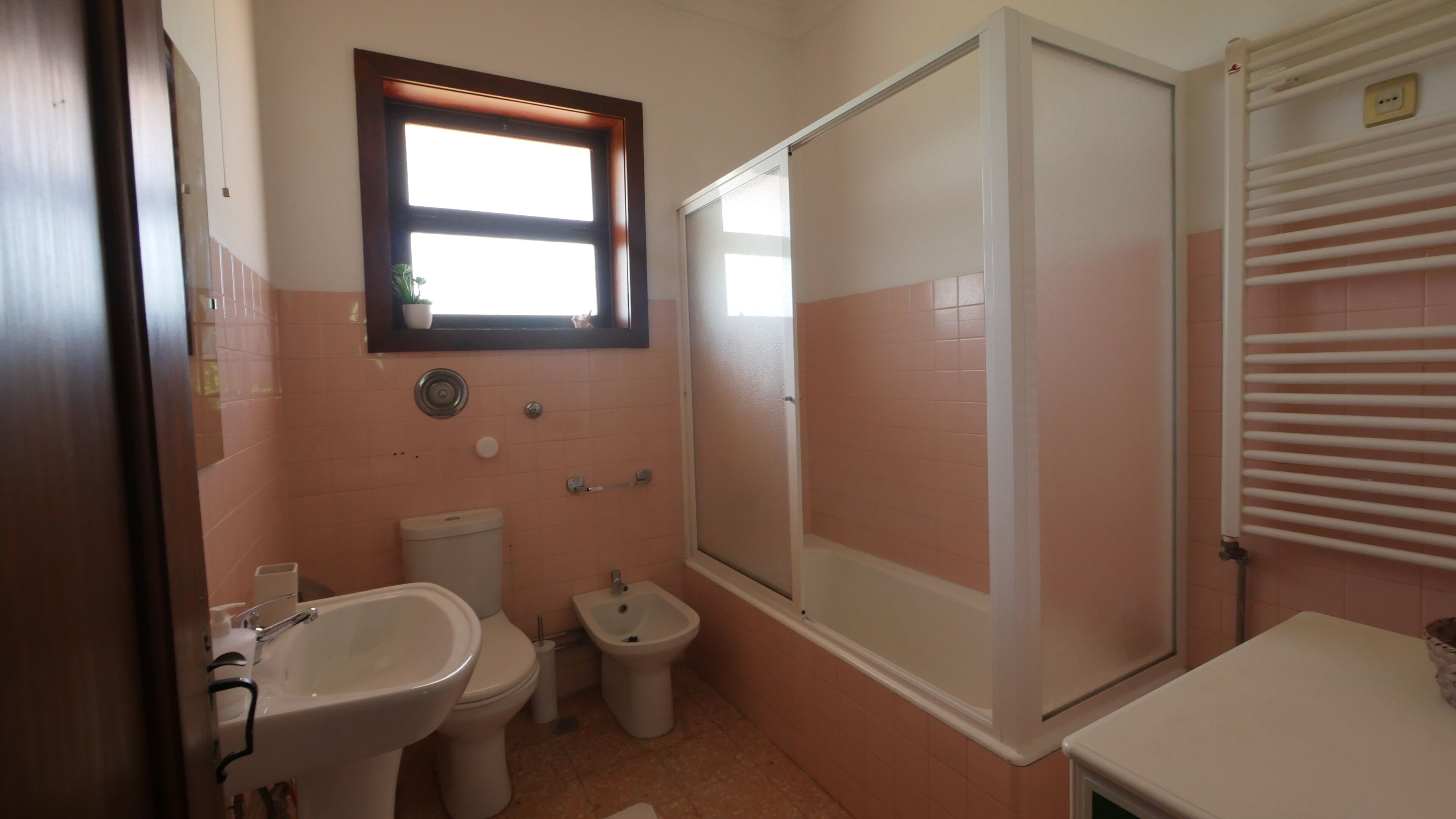 Casa de banho com sanita, bidé, lavatório e cabine de duche.