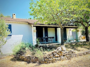 A house with a patio, outdoor seating, and a stone wall.