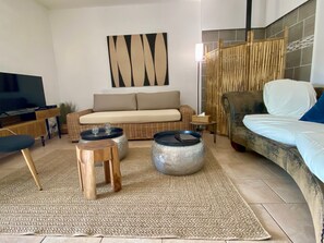 A living room with a sofa, a television, a coffee table, and a decorative wall piece. - L'Instant Bleu,Provence, pool, peaceful natural setting, 9p, Lake Carcès (Carcès)