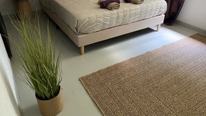 Une chambre à coucher avec un lit, une plante en pot, un tapis et une table de chevet.