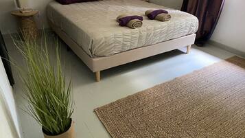 Une chambre à coucher avec un lit, une plante en pot, un tapis et une table de chevet.