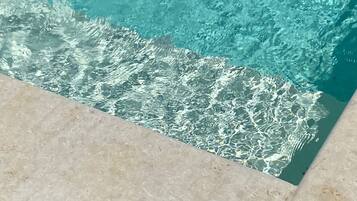 Une piscine à l’eau claire, dont les bords sont recouverts de carreaux.