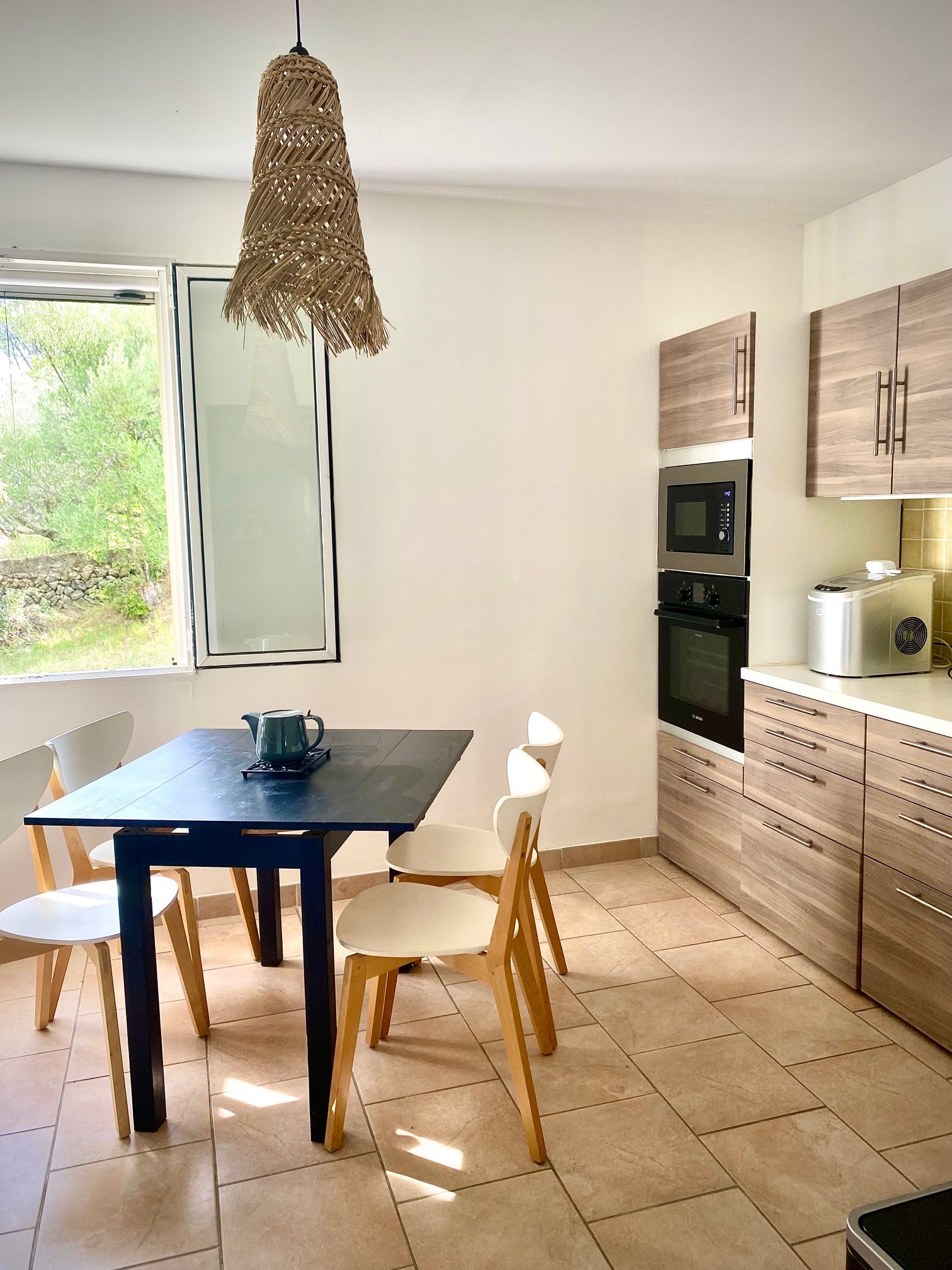 Une cuisine moderne avec une table à manger, des chaises et un luminaire suspendu.