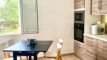 Une cuisine moderne avec une table à manger, des chaises et un luminaire suspendu.