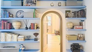 Una stanza con scaffali pieni di libri, una macchina da scrivere e una cornice con una fotografia appesa al muro.