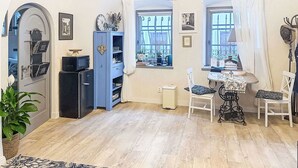Una stanza accogliente con pavimento in legno, un mobiletto blu, un tavolo con sedie e una finestra con tende.
