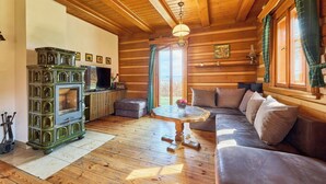 Interno di una baita con soffitto in legno, un caminetto, un divano e un tavolo da pranzo.