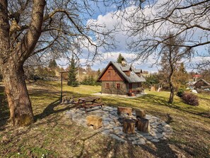 Eine rustikale Holzhütte mit einem Steinkamin, Holzsitzen und einem gepflasterten Weg.