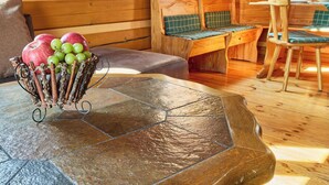 Un tavolo in pietra con una panca e sedie in legno nell'interno di una baita.