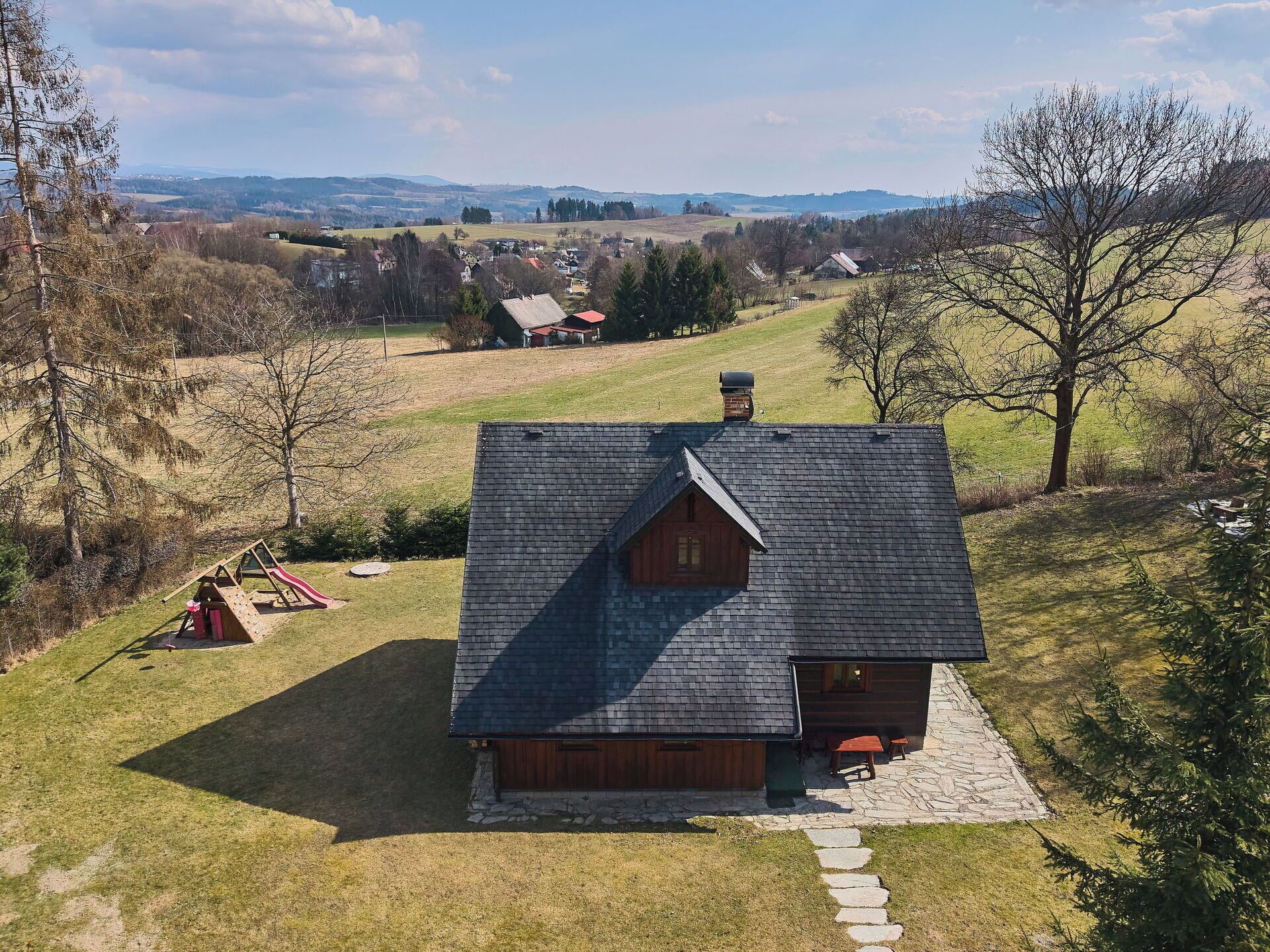A wooden cabin with a stone foundation, a sloped roof, and a stone path leading to the entrance.