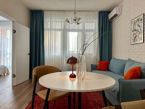 Un salon moderne avec une table ronde, des chaises, un canapé et un lustre.