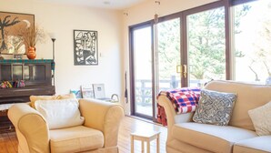 Ein Wohnzimmer mit zwei Sofas, einem Couchtisch, einem Kamin, Kunstwerken und großen Fenstern.
