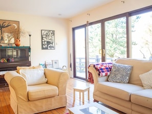 A living room with two sofas, a coffee table, a fireplace, artwork, and large windows.