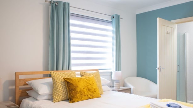 Ein Hotelzimmer mit einem Bett, einem Nachttisch mit Lampe, einem Stuhl und einer Tür.