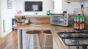 Eine moderne Küche mit eingebautem Toaster, Barhocker, Gasherd und einem flachbildfernseher an der Wand.