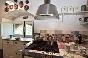 Een keuken met een gasfornuis, een hanglamp en een raam met uitzicht.