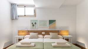 Een tweepersoonsbed met twee nachtkastjes, een raam met gordijnen en een wanddecoratie.