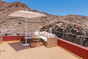 A terrace with a sofa, a table with drinks, and an umbrella. - Villa Chil - Luxury with heated pool and BBQ (Mogán)
