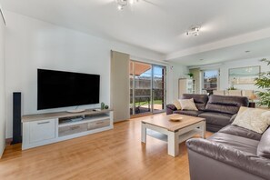 A modern living room with a flat-screen TV, leather sofa, and a dining area with a table and chairs. - Villa Chil - Luxury with heated pool and BBQ (Mogán)