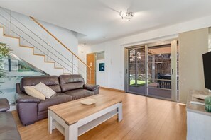 A modern living room with a staircase, a sofa, a coffee table, and a sliding glass door leading to an outdoor area. - Villa Chil - Luxury with heated pool and BBQ (Mogán)