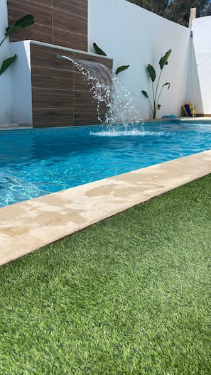 A swimming pool with a water feature, surrounded by a concrete deck and artificial grass. - Yasmine Hammamet near Carthage land a villa with swimming pool  (Yasmine Hammamet)