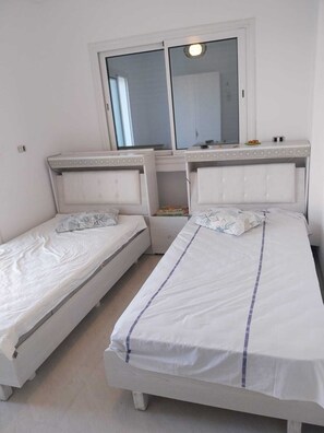 A room with two single beds, a window with a view, and a small table with a mirror above the beds. - Yasmine Hammamet near Carthage land a villa with swimming pool  (Yasmine Hammamet)