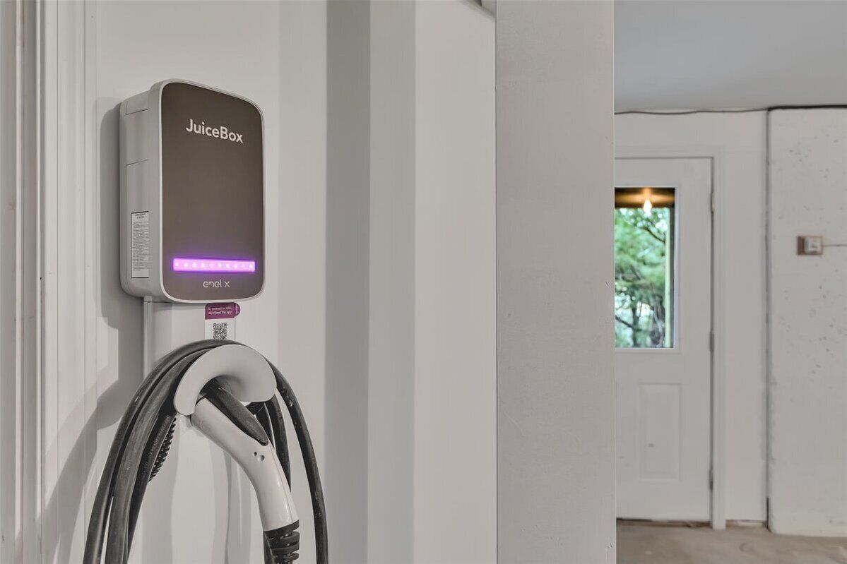 A JuiceBox charging station mounted on a wall with a door in the background.