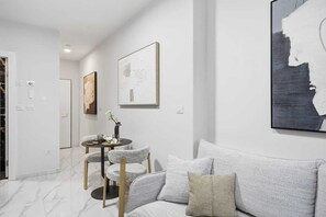 Ein modernes Wohnzimmer mit einer Couch, einem kleinen runden Tisch und Kunstwerken an den Wänden.