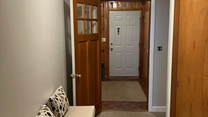 A hallway with a bench, a door, and a ceiling light. - Spacious 5-bedroom lake house in Standish, ME (Standish)