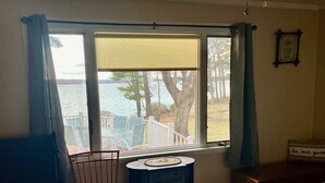 A bedroom with a view of a lake, a chair, a small table, and a bed. - Spacious 5-bedroom lake house in Standish, ME (Standish)