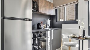 Une cuisine moderne dotée d’appareils électroménagers en acier inoxydable, un coin repas avec une table ronde et des chaises, et une grande fenêtre qui laisse entrer la lumière naturelle.