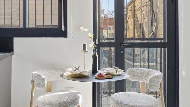 Un espace de salle à manger moderne, avec une table ronde, quatre chaises et une vue dégagée sur l’extérieur grâce à une grande fenêtre.