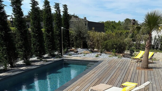 En træterrasse med liggestole og en swimmingpool.