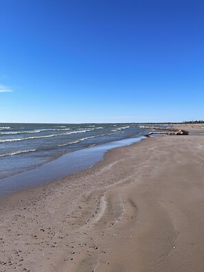 A beach with a clear sky, waves, and a sandy shore.