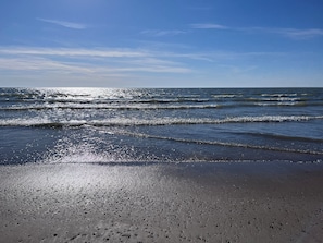 Une plage avec des vagues, un ciel dégagé et un rivage sablonneux.