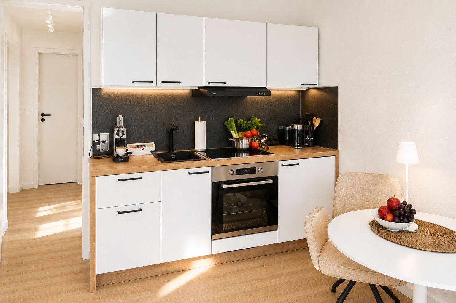 Cozinha moderna com armários brancos, forno embutido e máquina de café.