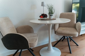 A modern room with two chairs, a small round table, a lamp, and a potted plant.