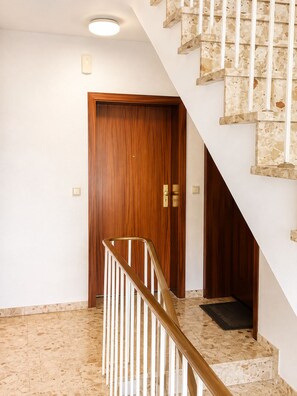 A staircase with a wooden handrail and a door at the bottom. - Vellmar Oase at Ahnepark with a terrace—quiet—24/7 self-check-in (Vellmar)