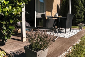 Eine Terrasse mit Tisch und StĂŒhlen, einem Blumentopf und einer Holzterrasse.