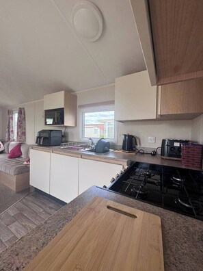 A compact kitchen with a stove, microwave, and sink.