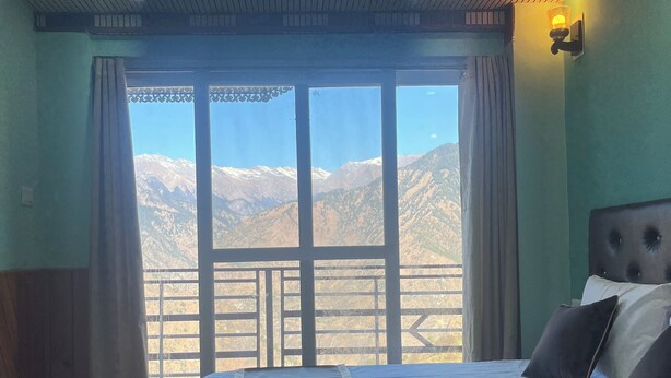 A bedroom with a bed, a view of mountains, and a balcony. - You home away from home in the mountains. (Shimla)