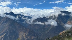 A mountainous landscape with snow-capped peaks, a clear sky, and a valley with scattered houses. - You home away from home in the mountains. (Shimla)
