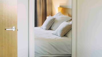 Un dormitorio con cama, cortinas y mesita de noche.