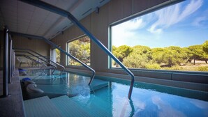 Ein Innenpool mit klaren Glaswänden, Metallhandläufen und Stufen zum Wasser.