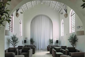 A spacious room with high ceilings, arched windows, and a large central curtain. - Progevita (Cofrentes)