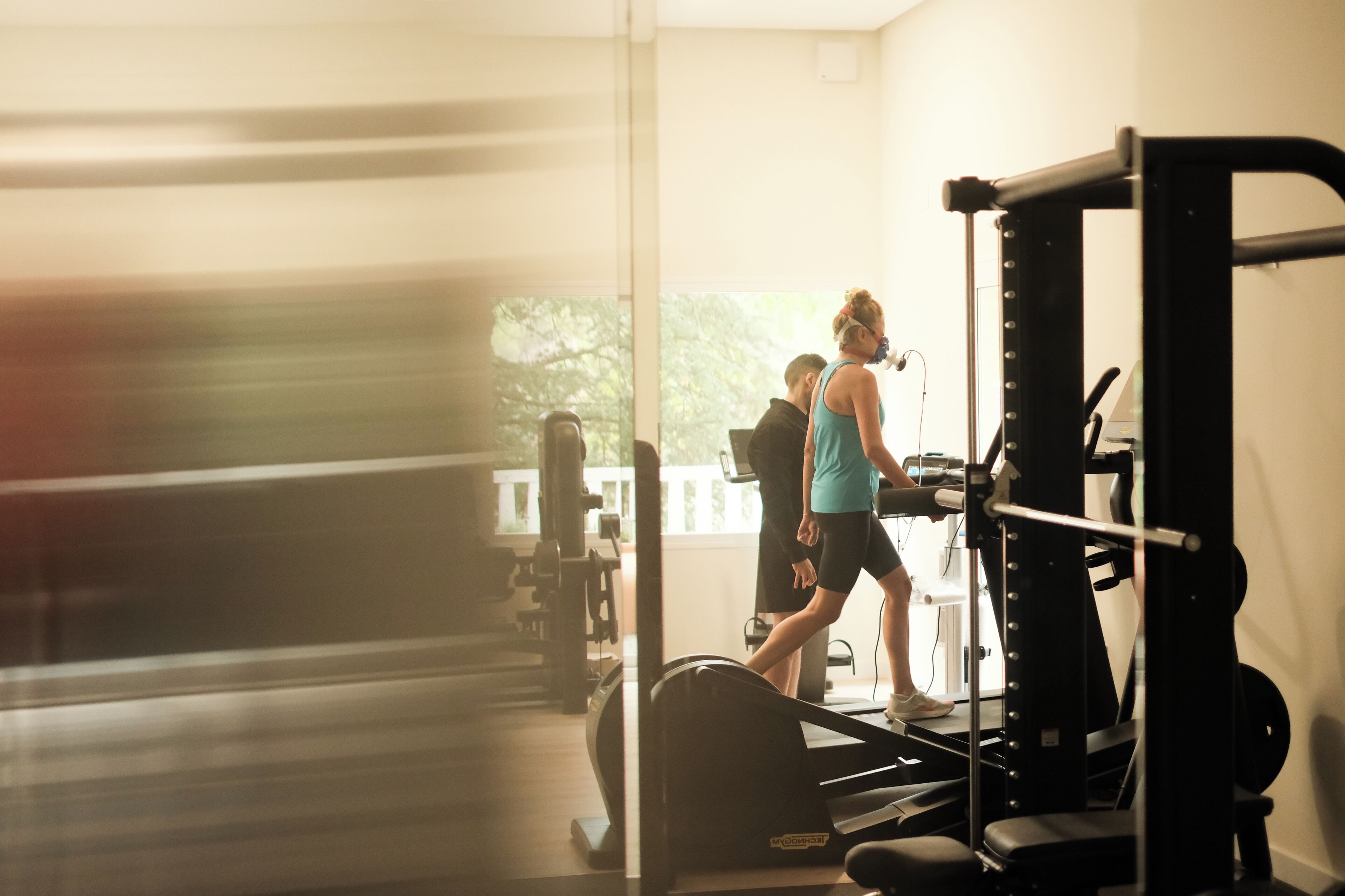 A gym with exercise equipment, a treadmill, and a person using the treadmill.