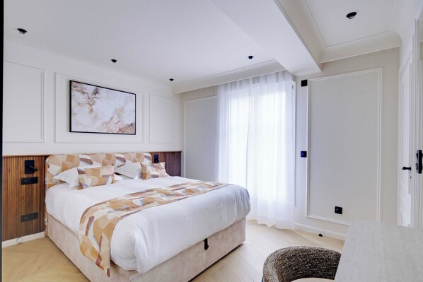 Une chambre à coucher avec un lit, une table de chevet, une chaise, une fenêtre avec des rideaux et une porte.