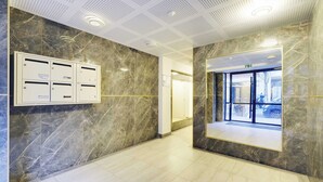 A hallway with marble walls, a reception desk, and a door leading outside. - Comftable Apartment a/c 1br/4p - Saint-mande (Saint-Mandé)