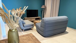 A living room with a sofa, a coffee table, a TV, and a vase with dried plants. - Villa Wonderfull sea view (Sari-Solenzara)